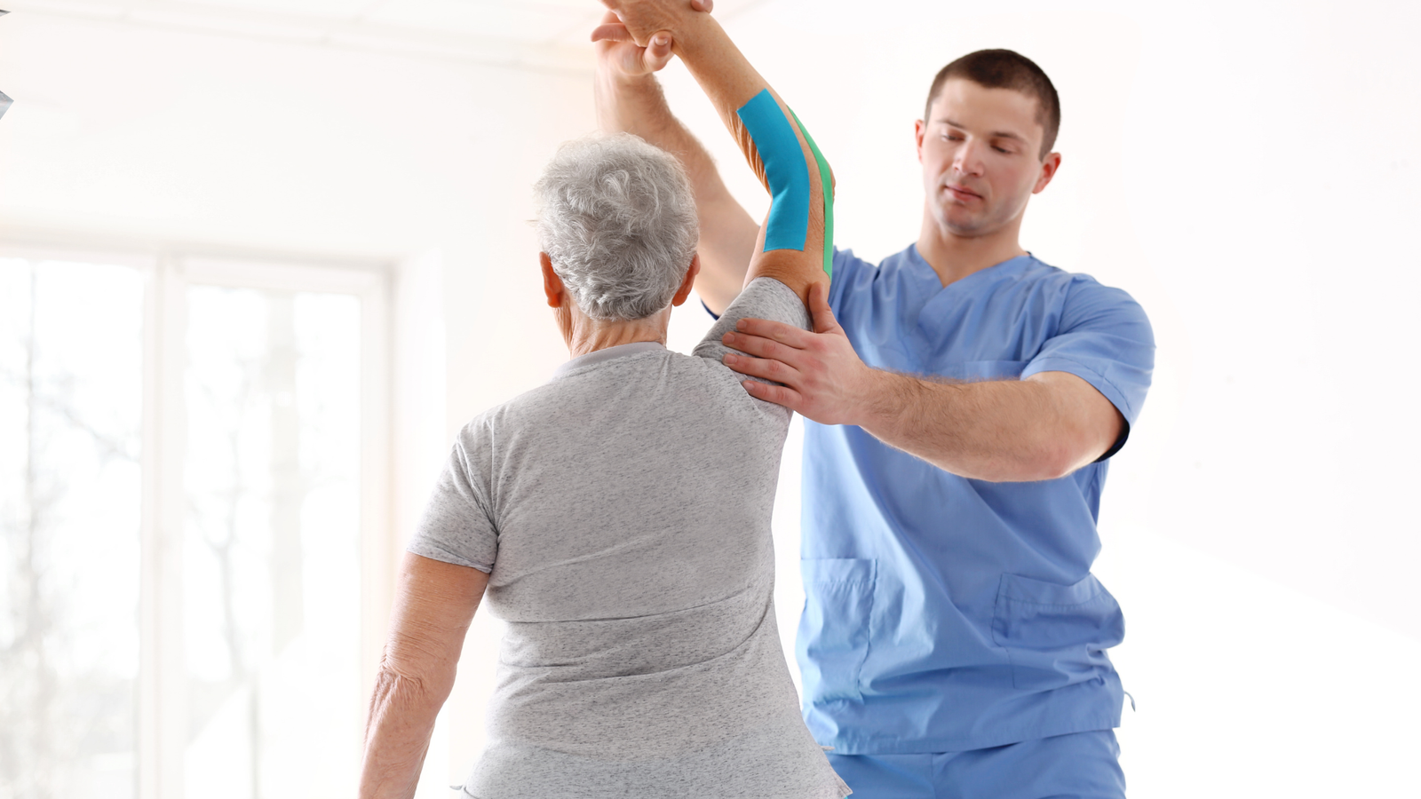 Fisioterapeuta realizando atendimento com idosa, aplicando técnicas de reabilitação física em consultório, representando serviço humanizado e profissional. landing page para fisioterapeuta